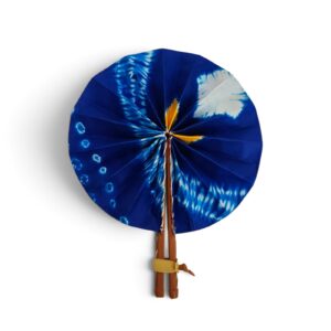 Éventail rond en tissu tie-dye bleu indigo et blanc avec manche en simili cuir marron et lien jaune.